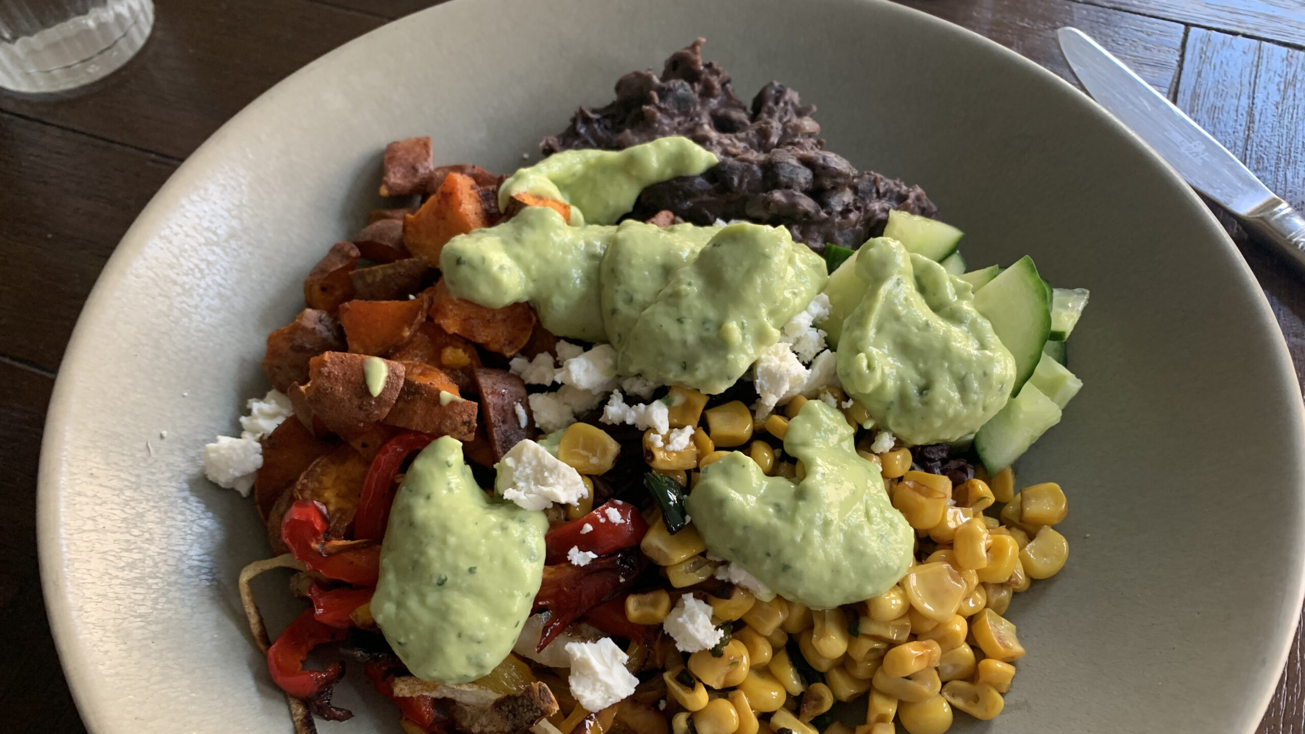 gerecht met verschillende groente, rijst, avocadosaus en feta